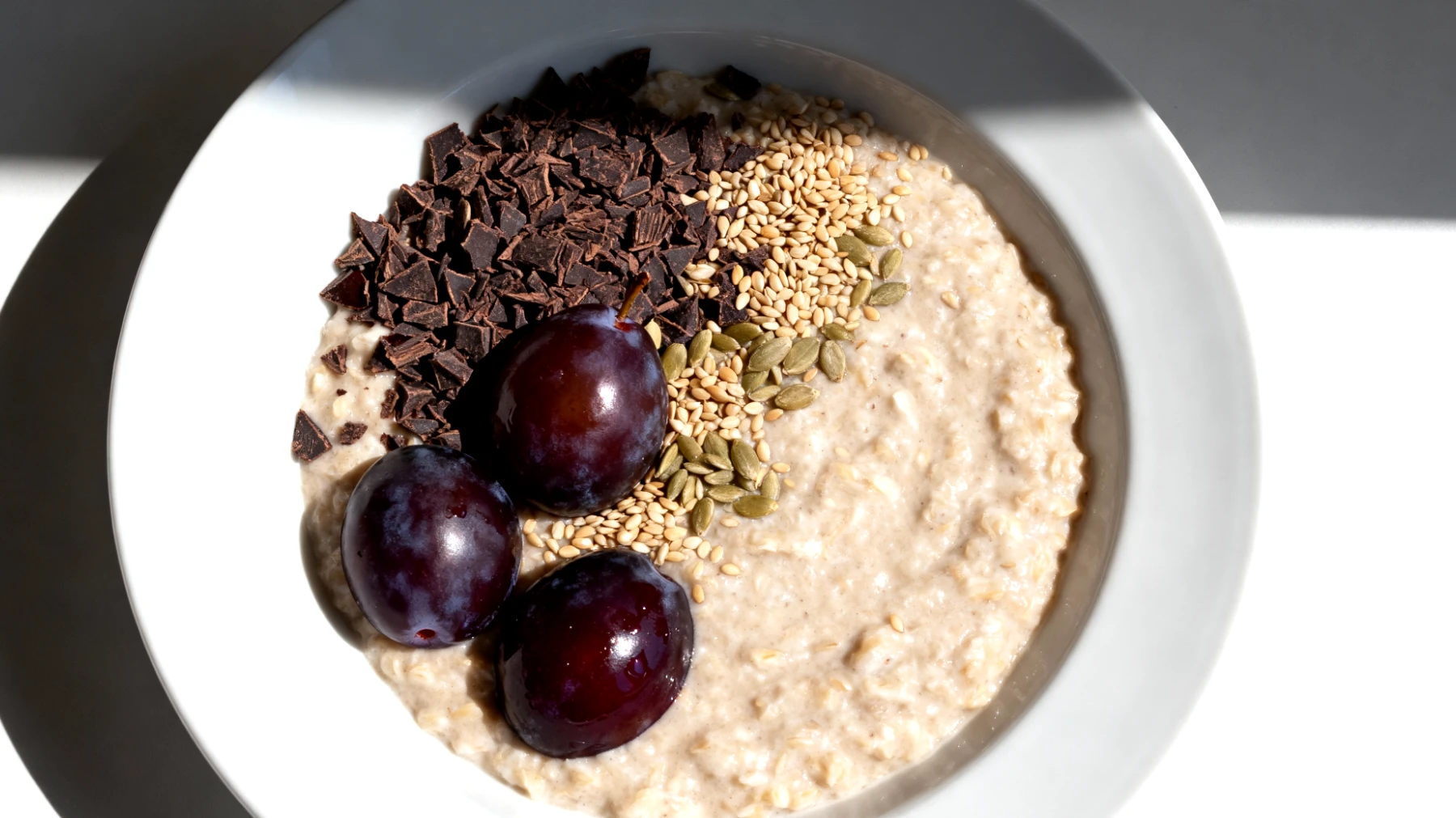 Hafer-Porridge mit Kakao-Nibs, Hanfsamen und fermentierten Pflaumen"